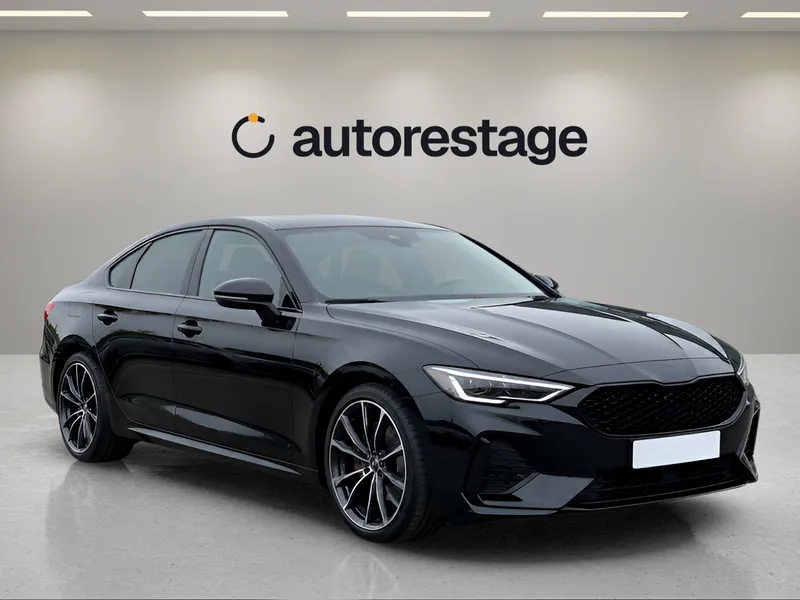 A black sedan in a white showroom with a logo on the wall behind it.