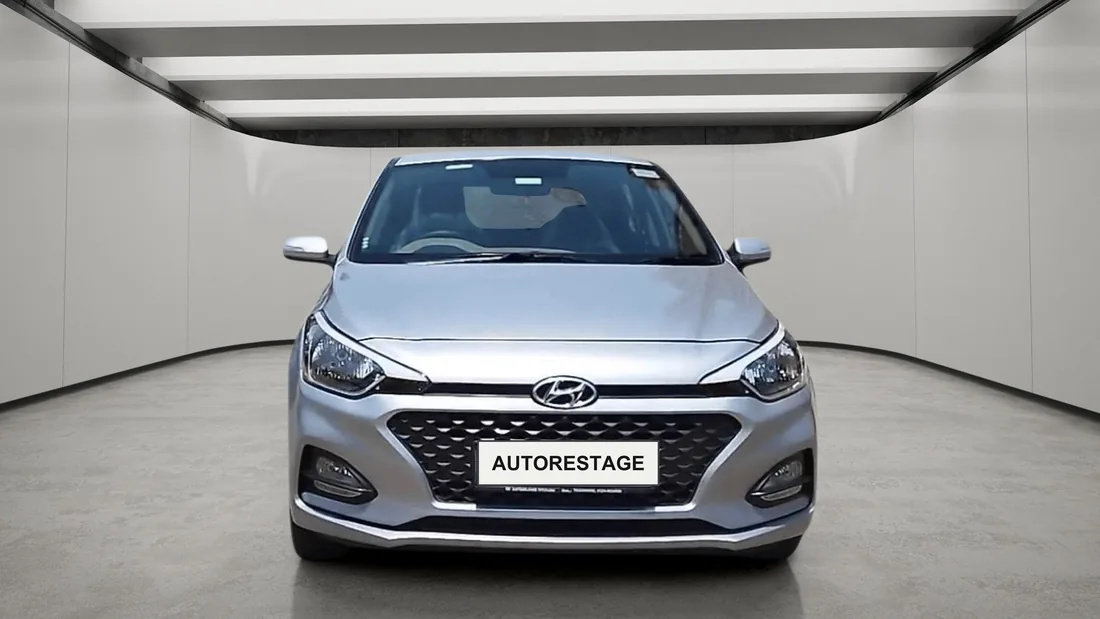 A silver hatchback on a lit studio floor, its reflection visible beneath it.
